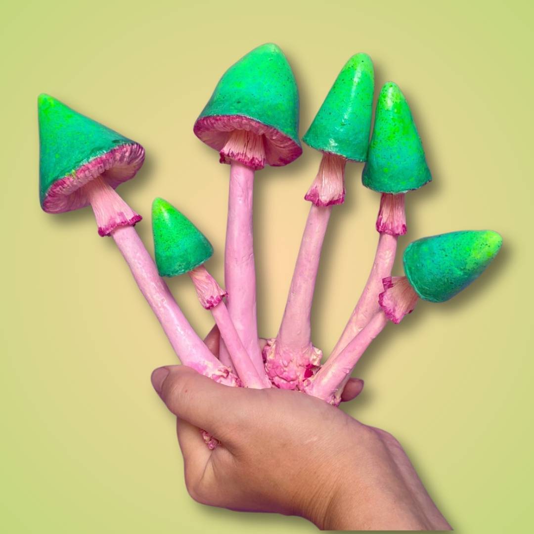 Whimsical papier-mâché fairy mushrooms with green caps – handmade craft held in hand on pastel background