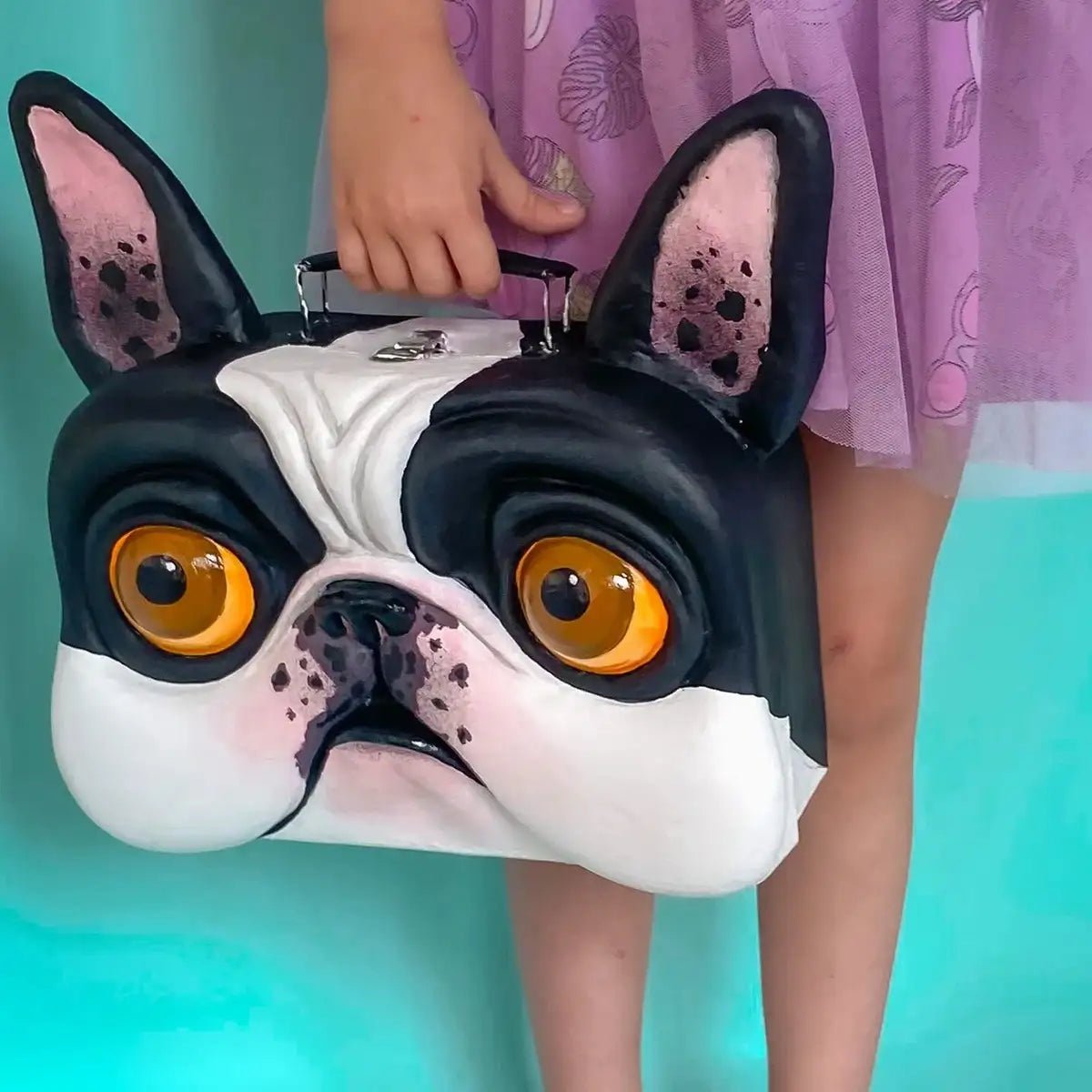 Handmade papier-mâché bulldog suitcase held by a girl in purple dress