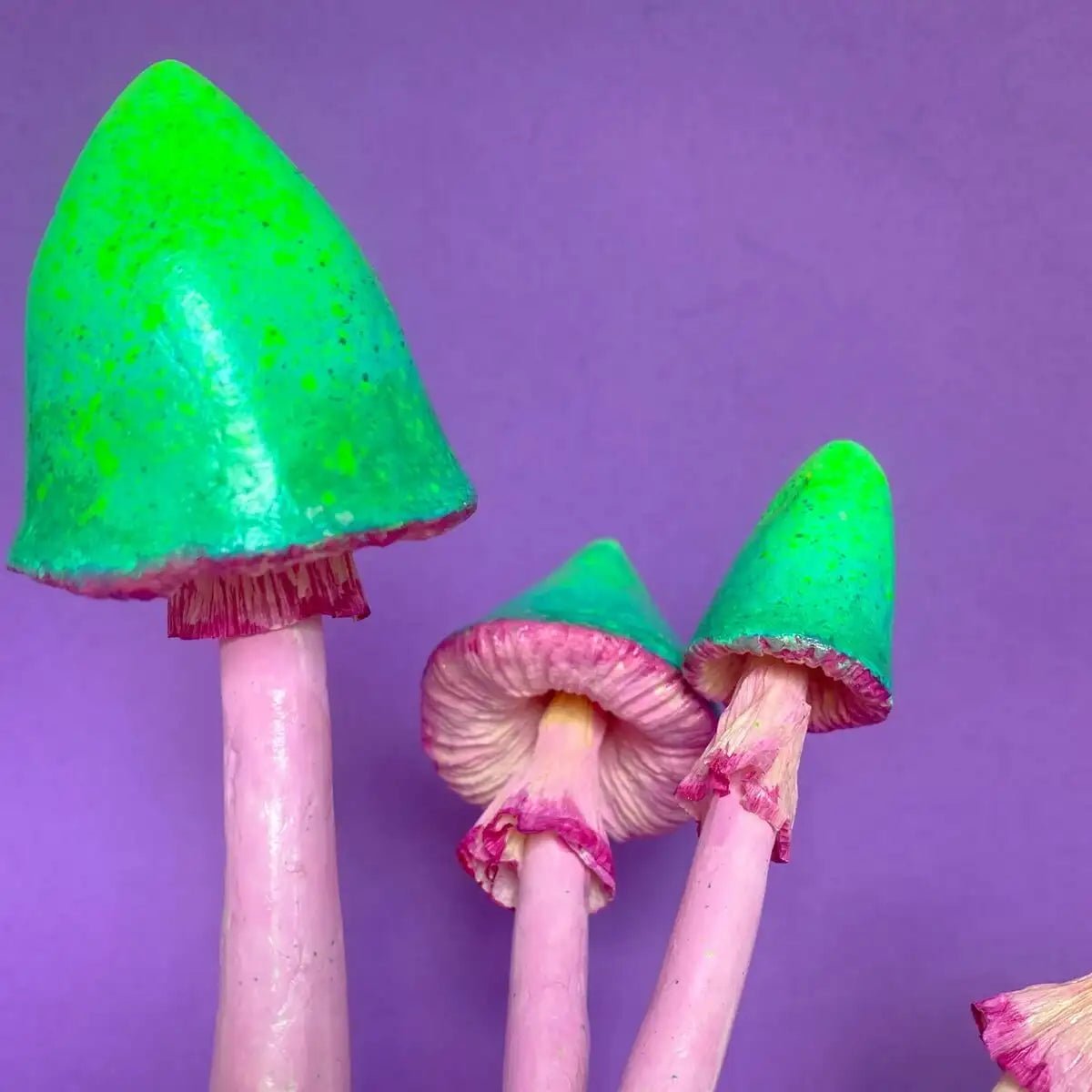 Angled shot of green and pink papier-mâché mushroom caps