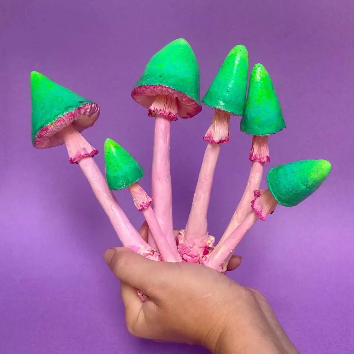 Papier-mâché mushroom set held in one hand against purple background