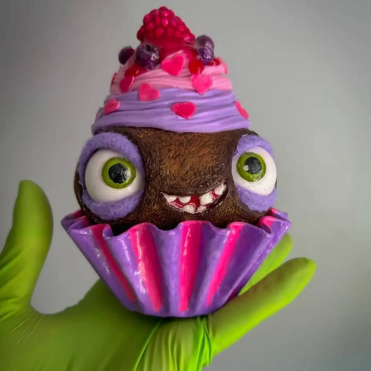 Papier-mâché cupcake held with green glove – smiling character