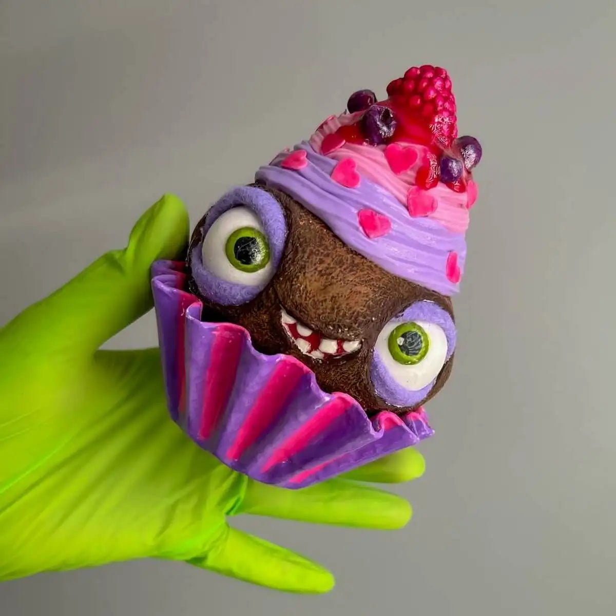 Side view of cupcake sculpture with green eyes and pink cup