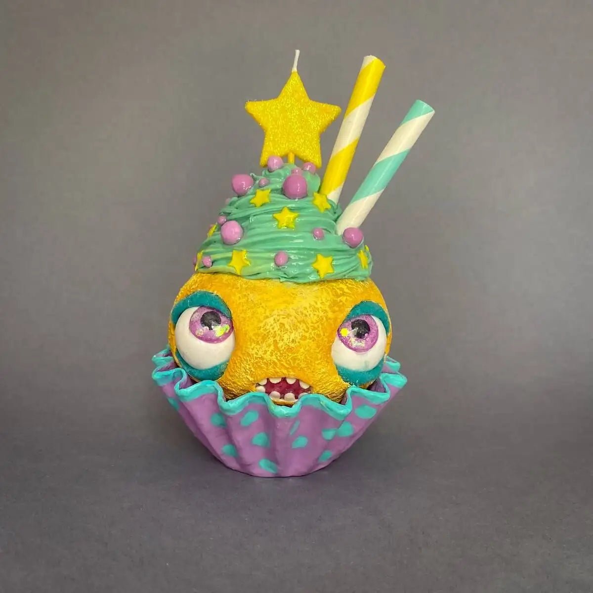 Front view of papier-mâché cupcake sculpture with moving eyes and candle