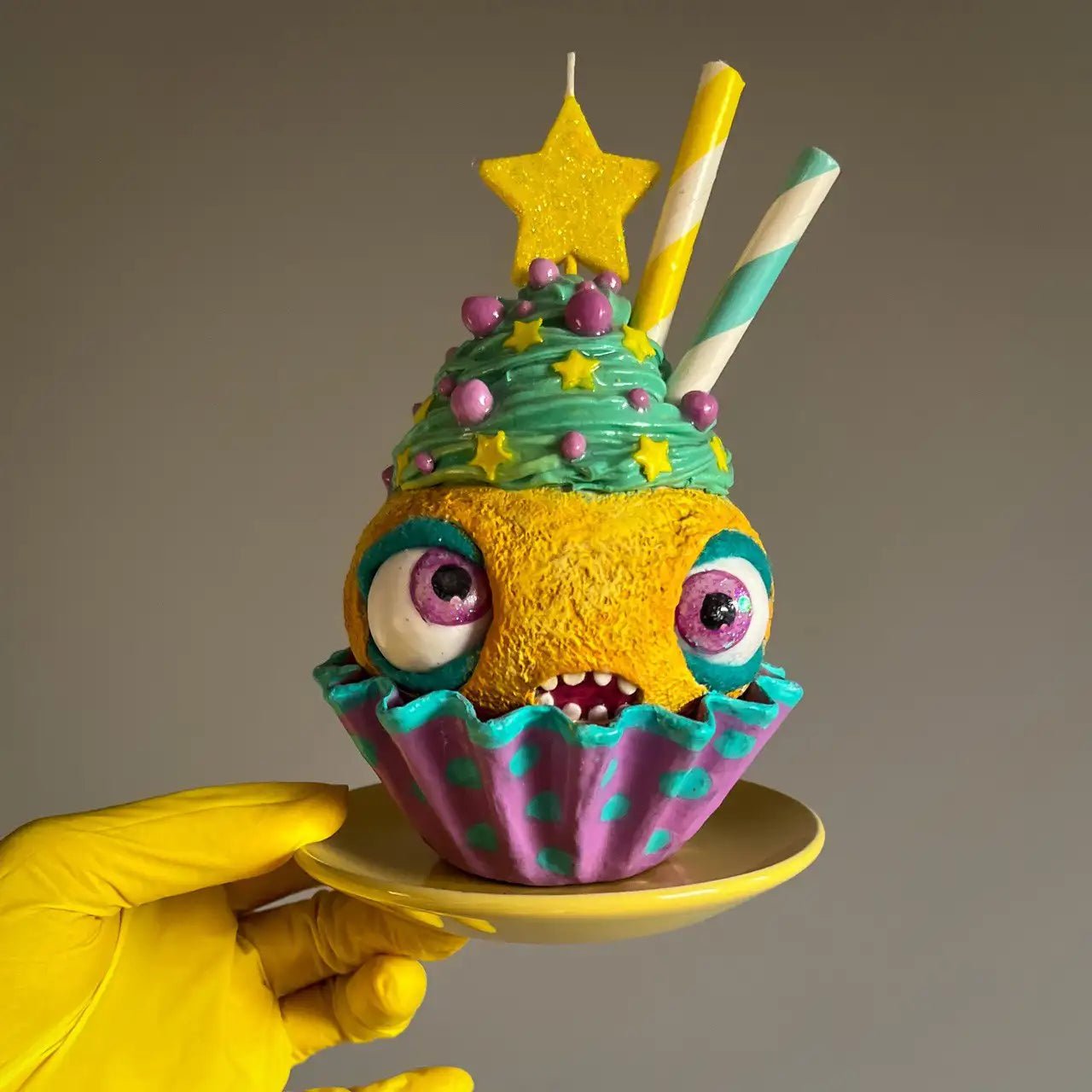 Cupcake sculpture on plate, side angle with visible candle