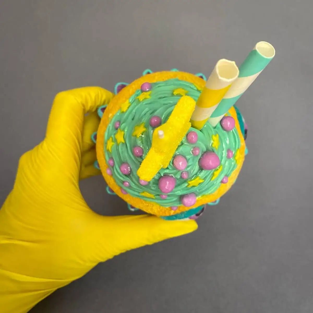 Top view of whimsical cupcake sculpture with star candle and straws