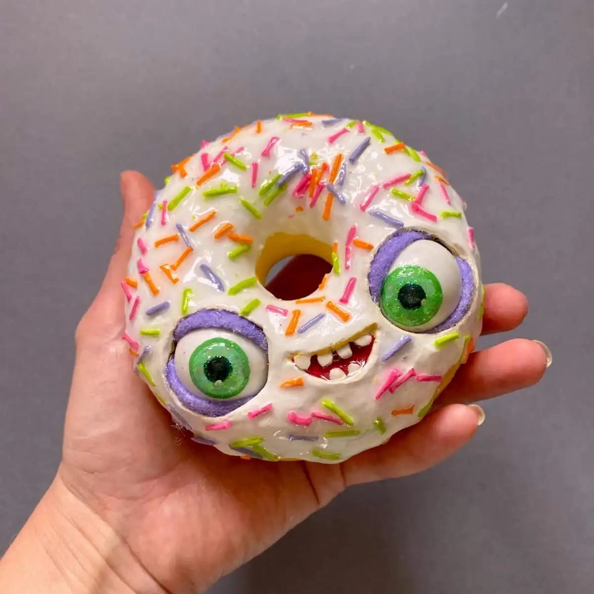 Funny white papier-mâché donut with moving eyes held in hand