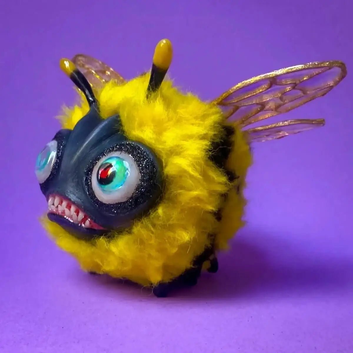 Side angle of fluffy bee figurine with iridescent wings and striped fur
