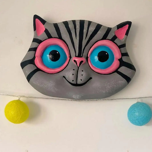 Front view of gray papier-mâché cat wall sculpture with pink glasses
