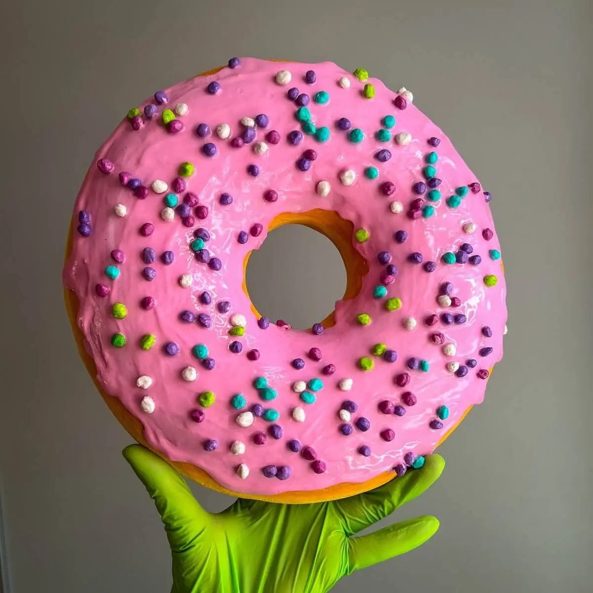 Handmade pink donut made of papier-mâché – held in hand, playful design