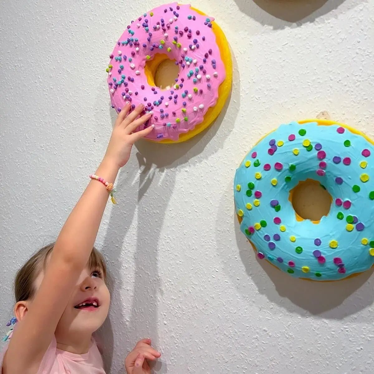 Child reaching for large papier-mâché donuts – wall decor for kids' room