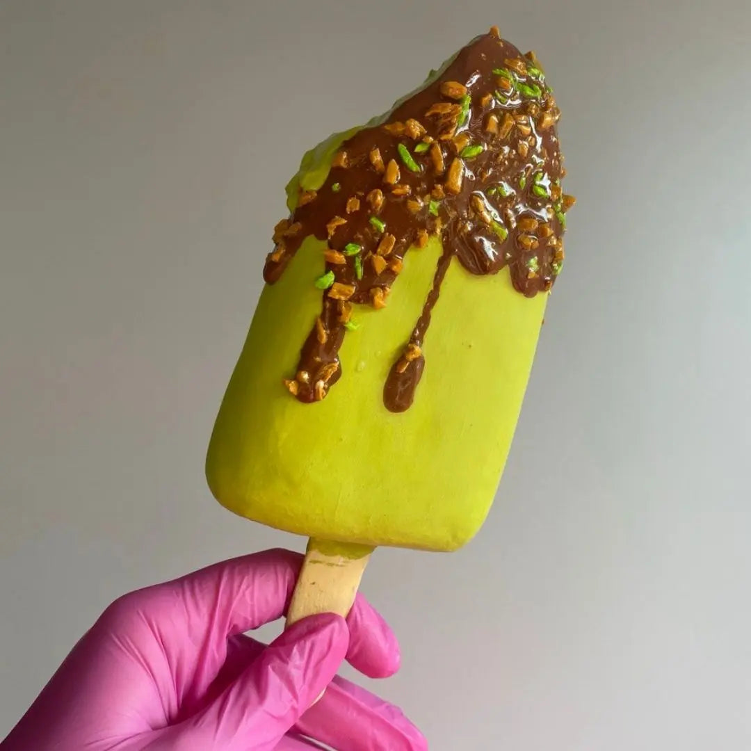 Handmade papier-mâché ice cream popsicle in green color with caramel and nuts decoration