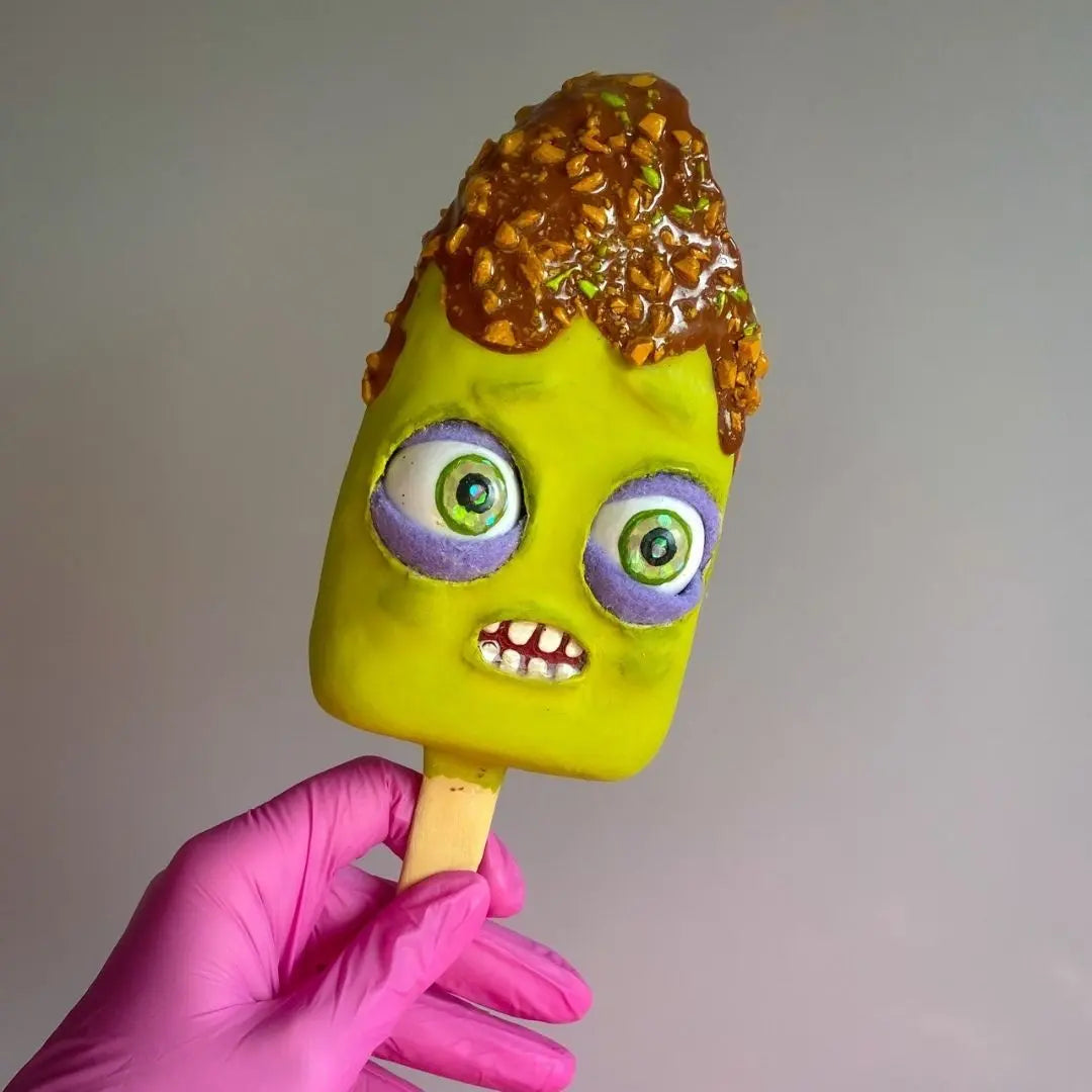 Papier-mâché ice cream popsicle with funny green face and caramel nut topping