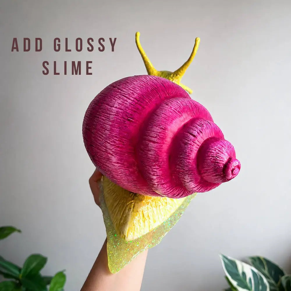 Handmade papier-mâché snail with a bright pink shell and glossy slime effect