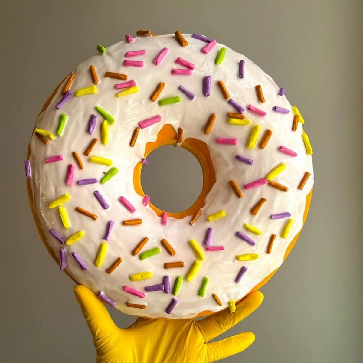 White papier-mâché donut sculpture with pink sprinkles – front view