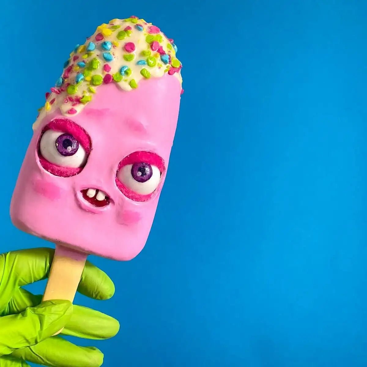 Pink papier-mâché ice cream sculpture held in hand – front view