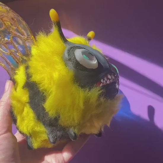 Video showing handmade fluffy bee figurine being rotated in hand under natural sunlight