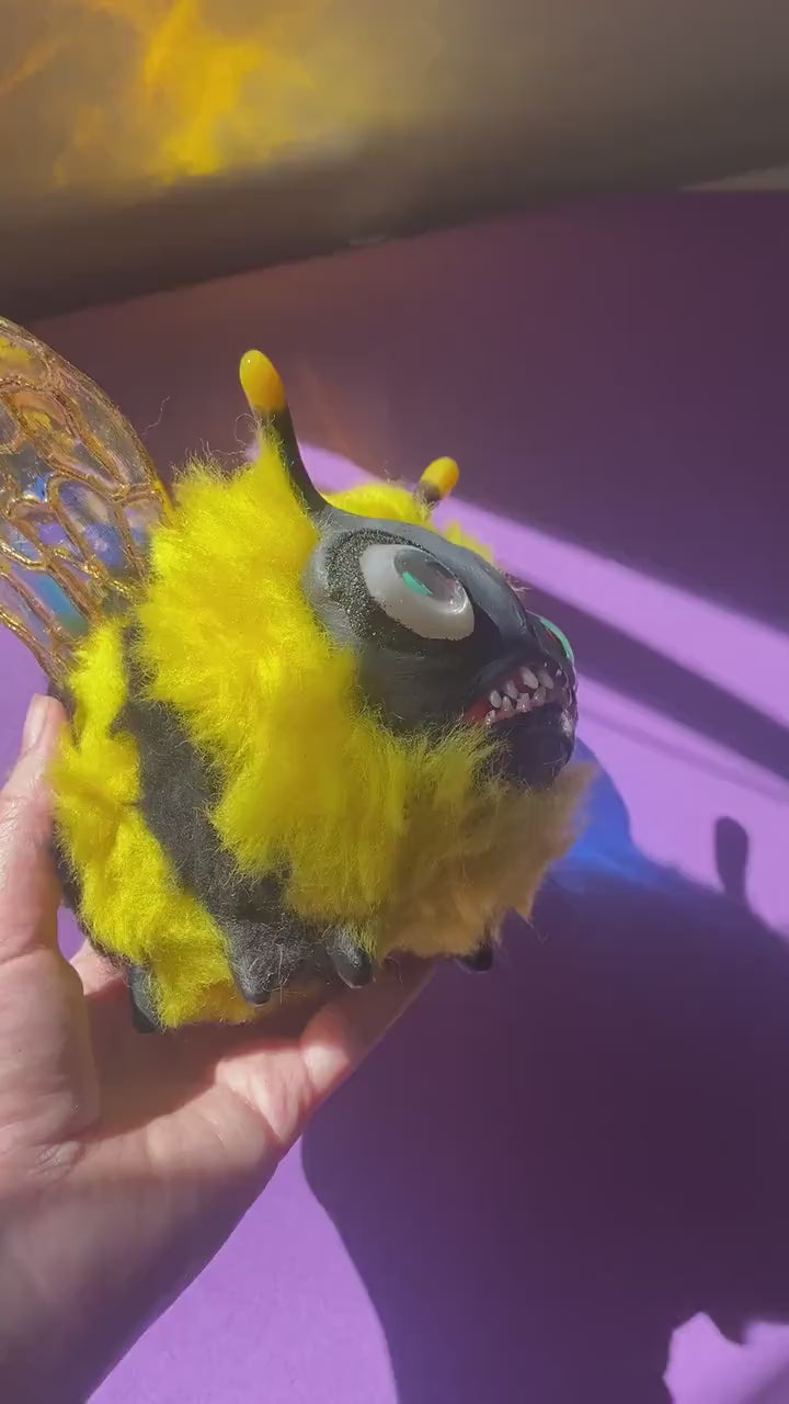 Video showing handmade fluffy bee figurine being rotated in hand under natural sunlight